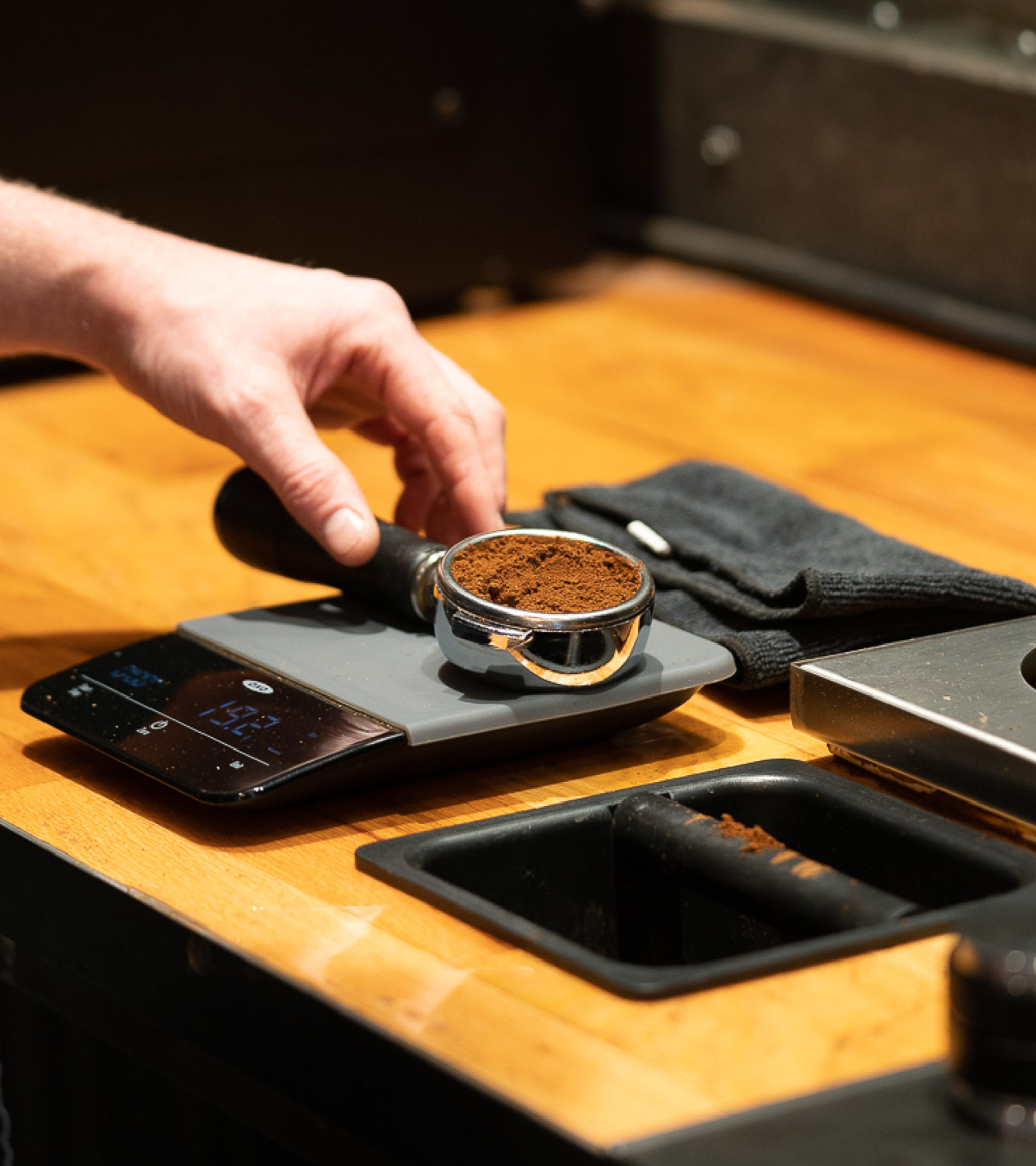 Impossible Coffee expert demonstrating how to tamp an espresso portafilter on a scale