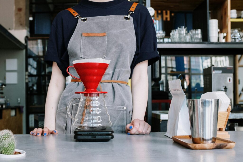 A pourover is taking place as a barista stands behind a bench