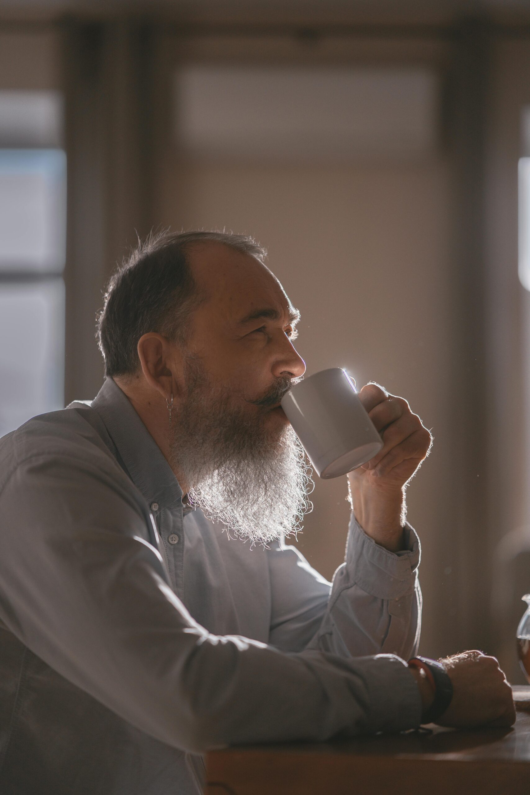 A man with a beard is sipping coffee at a company coffee tasting event in the sunshine